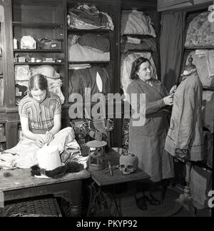 1950s, historical, a lady and a young woman working in a costume store room preparing period dress and theatrical outfits and stage props, England, UK. Stock Photo