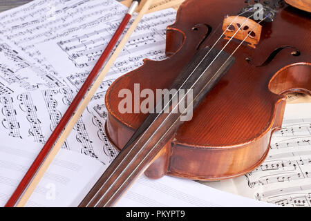 Vintage violin on musical notes. Old viola and musical notes sheets. Classical music background. Stock Photo