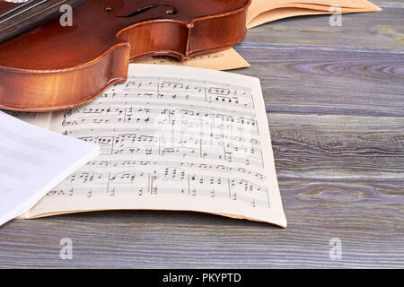 Sheets of musical notes and violin. Vintage musical instrument on old wooden background. Music still life. Stock Photo