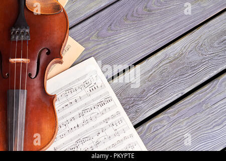 Violin on old wooden boards. Sheets of musical notes and violin on wooden surface with text space. Stringed instrument of classical music. Stock Photo