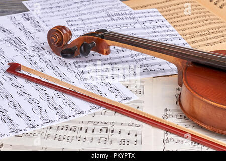 Musical background with old violin. Vintage viola and fiddle stick on musical notes sheets close up. Lesson of classical music. Stock Photo