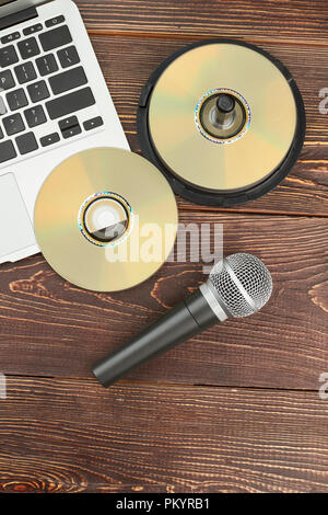 Old and modern devices on wooden table. Portable laptop, compact discs and microphone on wooden background, top view. Technology progress concept. Stock Photo