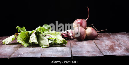 Red Beetroot with herbage green leaves on rustic background. Organic Beetroot. Stock Photo