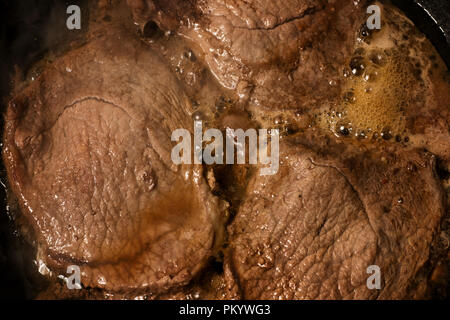 Steak fried in a frying pan close up. Cooking of the meat top view Stock Photo