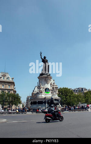 Man rides motorcycle in front of the statue (by Leopold Morice - 1880) of Republic square (Place de la Republique) in Paris. Stock Photo