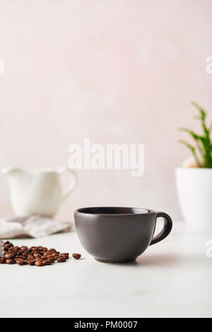 Espresso in a matte black ceramic coffee cup with roasted coffee beans. Feminine rose background with copy space. High resolution image. Stock Photo