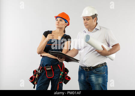 An architect man wearing a hard hat or helmet and co-worker builder woman reviewing blueprints Stock Photo