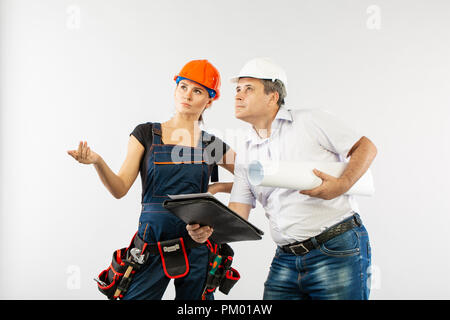 An architect man wearing a hard hat or helmet and co-worker builder woman reviewing blueprints Stock Photo