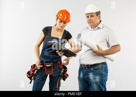 builders in hardhat or helmet discussing blueprints with tablet Stock Photo