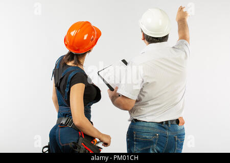 builders in hardhat or helmet discussing blueprints with tablet Stock Photo