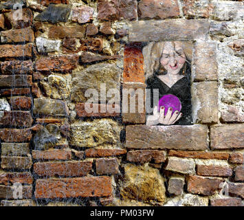 Halloween scary witch holding a glass sphere window peek through a brick wall full of spider webs Stock Photo