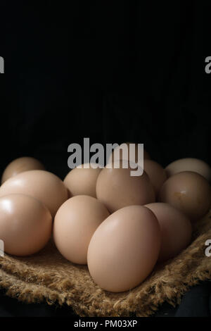 Eggs in a nest on hemp sack, dark corner. Stock Photo