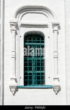 Church window with iron bars from the street. White building. Stock Photo
