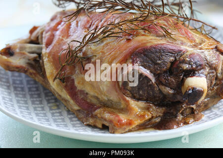 Freshly cooked roast lamb shoulder on a plate with a rosemary herb garnish Stock Photo