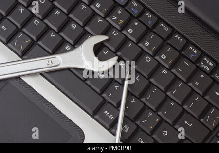 A wrench and a screwdriver on the laptop keyboard Stock Photo