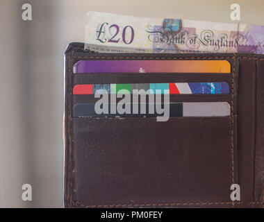 Brown leather wallet, open with three cards inside and cash sticking out of the top Stock Photo
