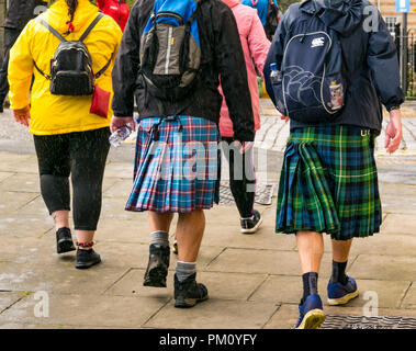 Leith, Edinburgh, Scotland, UK, 16th September 2018. Edinburgh Kilt Walk, sponsored by the Royal Bank of Scotland, takes place today. Walkers raise funds for a charity of their choice. The kilt walkers reach The Shore in Leith at about Mile 14. Men carrying backpacks wearing kilts with swinging pleats walk past Stock Photo