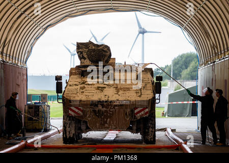 Emden, Germany. 16 September 2018. Bundeswehr employees cleaning an armoured Bundeswehr transport vehicle, which is to be loaded onto a RoRo ship afterwards, on the grounds of Emden harbour. The NATO exercise 'Trident Juncture 2018 (TRJE 18)' will take place in Norway from 25 October to 7 November. The Bundeswehr is to transfer almost 10,000 soldiers and more than 4,000 vehicles to Norway. A ship is being loaded with around 300 vehicles and tanks as well as 95 containers in the port of Emden. Photo: Mohssen Assanimoghaddam/dpa Stock Photo