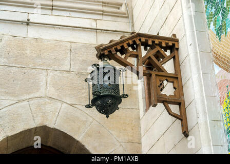 Old iron lantern with a cross hanging from a wooden frame on a stone wall of an old church of Coptic religion Stock Photo