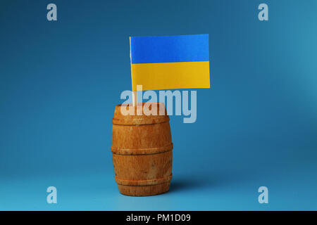 A beautiful paper flag of Ukraine on wooden stick in wooden barrel. Blue background Stock Photo