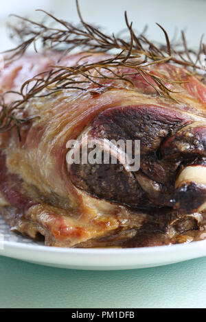 Freshly cooked roast lamb shoulder on a plate with a rosemary herb garnish Stock Photo