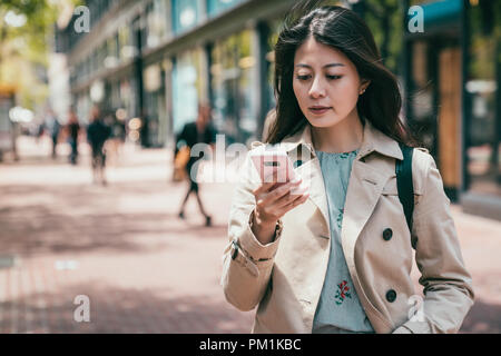 confident business woman looking at her phone and sending orders to her subordinates Stock Photo