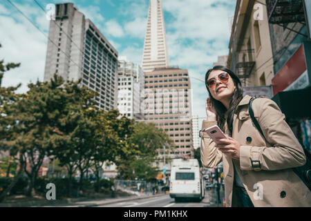 attractive and young female visiting a morden city and  looking happily while standing in the street. Stock Photo