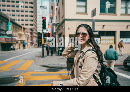 pretty fashionable woman walking in the street and smiling happily to the camera with a excited look. Stock Photo