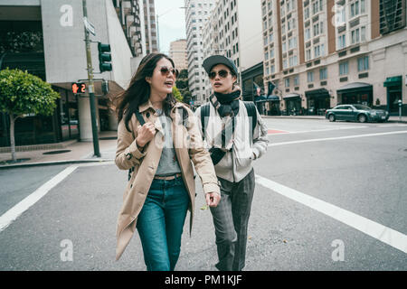 tow good friends walking across the road and hanging out with each other in downtown. Stock Photo