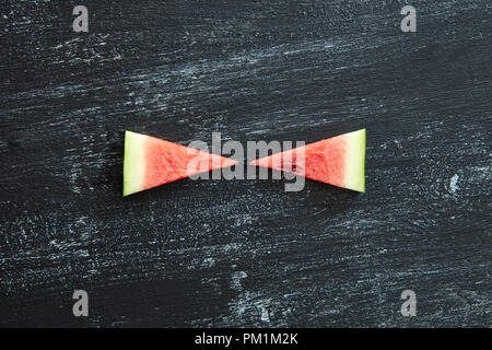 Two triangular pieces of fresh watermelon on a black concrete background with copy space. Summer vitamin dessert. Flat lay Stock Photo