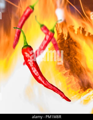 a few pieces of red chili peppers on background with fire Stock Photo