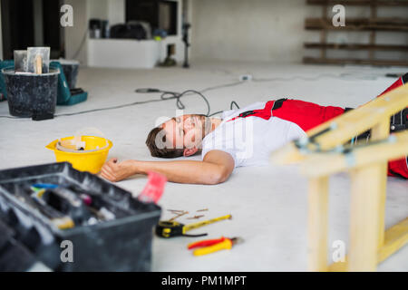 A man worker lying on the floor after an accident at the construction site. Stock Photo