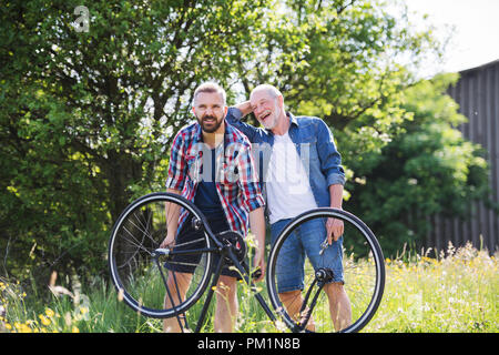 An adult hipster son and senior father repairing bicycle puncture n a sunny day. Stock Photo