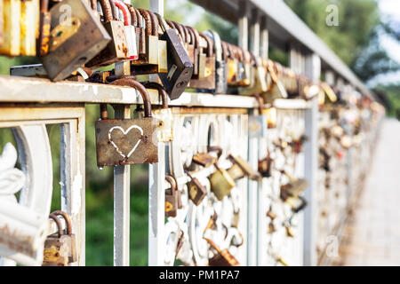 Red heart padlock locked on fence. Lock in shape of heart as symbol of eternal love. Stock Photo