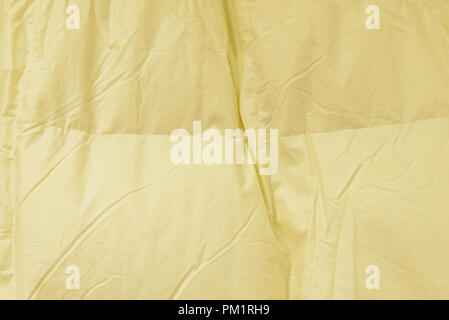 Soft warm cotton fabric beige wrinkled bed sheet texture background. Trendy soft color feathery touch-feel bed linen sheet texture. Stock Photo