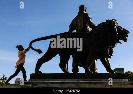 Victoria Memorial, London, UK, 17th Sep 2018. People form silhouettes as they pose next to the bronze 'man and lion' statue at Victoria Memorial, Buckingham Palace, against the bright blue sky in warm late afternoon sunshine. Credit: Imageplotter News and Sports/Alamy Live News Stock Photo