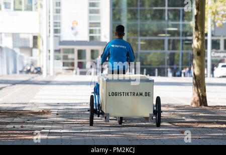 17 September 2018, Hessen, Frankfurt Main: A box used to transport goods being transported on a bicycle trailer on the exhibition grounds. The pilot project 'Logistiktram' is to serve the climate-friendly transport of goods. Photo: Silas Stein/dpa Stock Photo