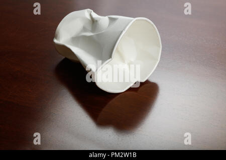 Crumbled White paper coffee cup on table. Stock Photo