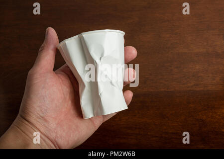 Crumbled White paper coffee cup on table. Stock Photo