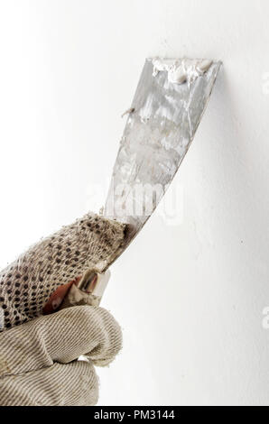 Detail of a male hand plastering  a wall with old spatula and putty. Stock Photo