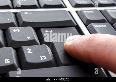 Closeup of a finger pushing enter button. Stock Photo