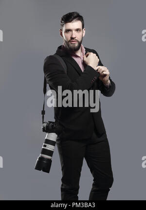 professional photographer with camera, adjusting a cufflink.isolated on grey background Stock Photo