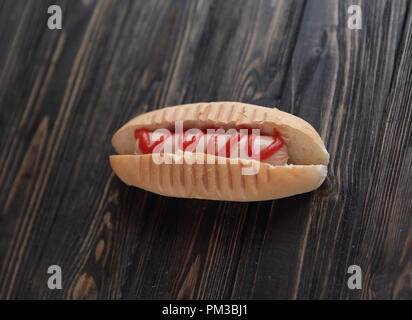 hotdog with tomato sauce on dark wooden background.photo with co Stock Photo