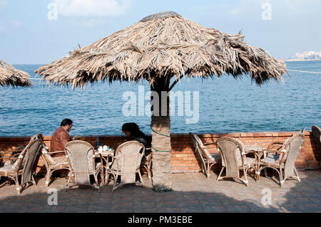Egypt, Alexandria, 2014. A couple sit at a cafe table next to the Mediterranean sea. Stock Photo