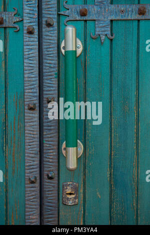 An old green closed door with large door handles and a keyhole Stock Photo