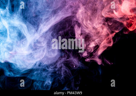 Dense multicolored smoke of  pink,  blue and purple colors on a black isolated background. Background of smoke vape Stock Photo