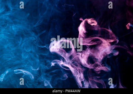Thick colorful smoke of red, pink and  blue on a black isolated background. Background from the smoke of vape Stock Photo