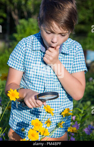 Shocked boy with magnifying glass in garden Stock Photo