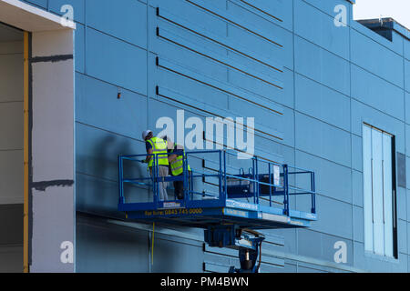 workmen working on a raised platform with protective clothing, uk Stock Photo