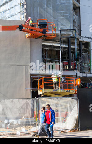 workmen working on two raised platforms with protective clothing, uk Stock Photo